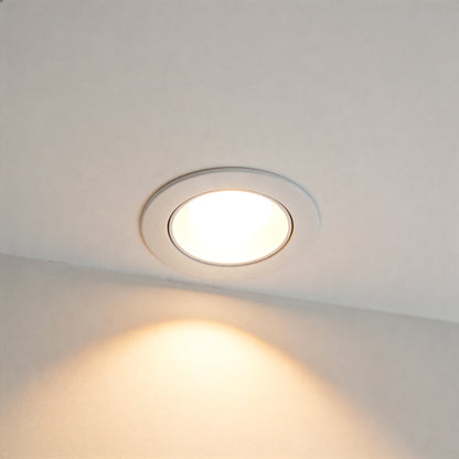 White circular LED downlight recessed into clean white ceiling with warm light beam