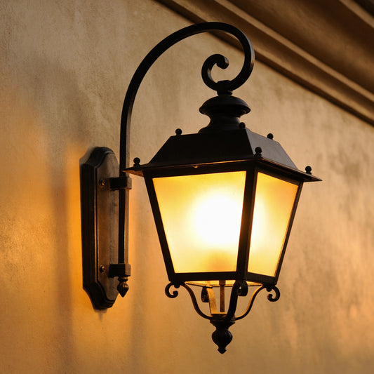 Elegant black traditional half wall lantern mounted on rendered exterior wall at dusk