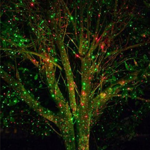 Red and green laser Christmas lights projected onto a tree outdoors